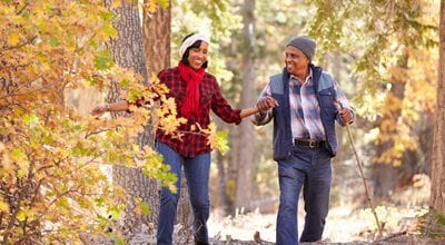 older couple with walking sticks walking in woods