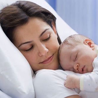 Mom in hospital bed holding newborn.